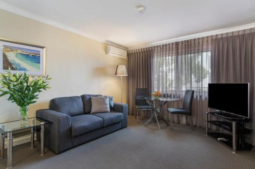 a living room filled with furniture and a tv at The Peninsula Riverside Serviced Apartments in Perth