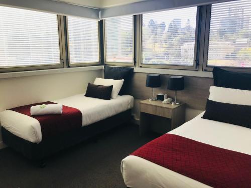 a hotel room with two beds and windows at George Williams Hotel in Brisbane