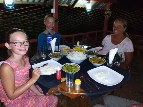 a group of people sitting around a table with food at Sigiri Royal Point Tree House in Sigiriya