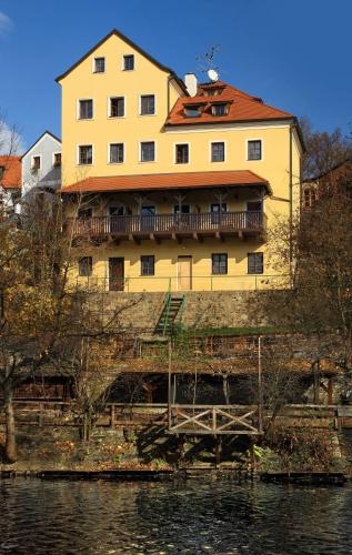 a large yellow building sitting on the side of a river at Hotel Garni Myší Díra in Český Krumlov