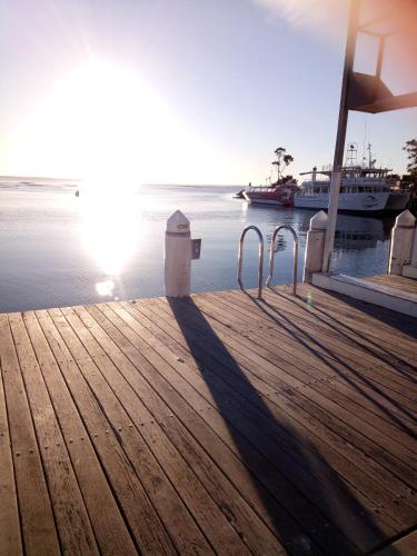 a wooden dock with a boat in the water at The Husky House or Little Husky Studio Suite in Huskisson