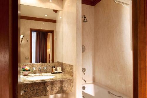 a bathroom with a sink and a mirror and a tub at Hôtel Horset Opéra, Best Western Premier Collection in Paris