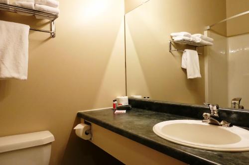 a bathroom with a sink and a mirror and a toilet at Super 8 by Wyndham Dauphin in Dauphin
