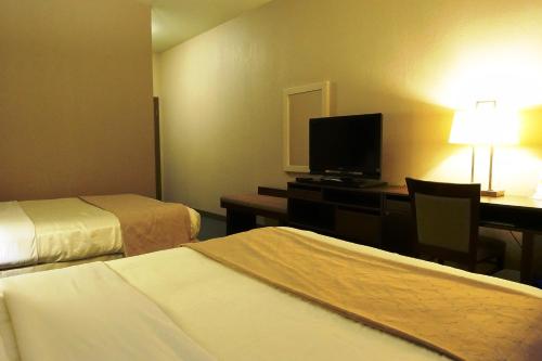 a hotel room with two beds and a desk with a television at Super 8 by Wyndham Dauphin in Dauphin