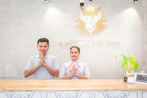 a man and a woman standing in front of a table praying at Grand Elevation Hotel in Phnom Penh
