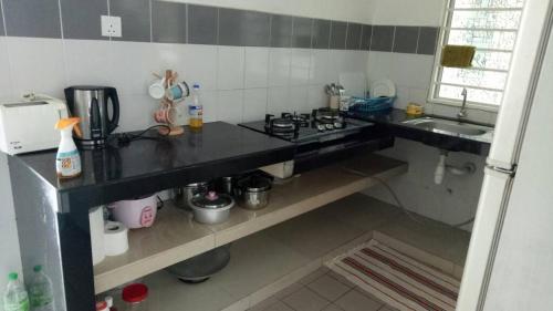 a small kitchen with a stove and a sink at Affordable Stay @ Rue’s Villa Tropika Apartment, UKM Bangi in Bangi