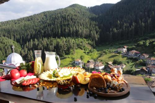 a table of food with a view of a mountain at Family hotel Valchanovata Kashta in Fotinovo