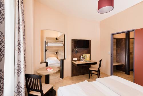 a hotel room with a bed and a desk and a bedroom at JUFA Hotel Fürstenfeld in Fürstenfeld