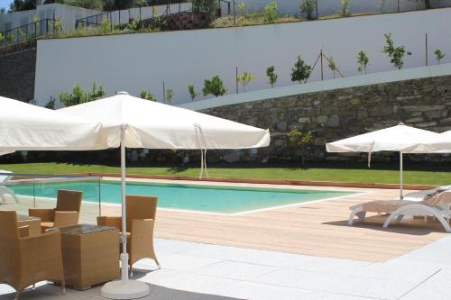 a swimming pool with umbrellas and chairs and a swimming pool at Delfim Douro Hotel in Lamego
