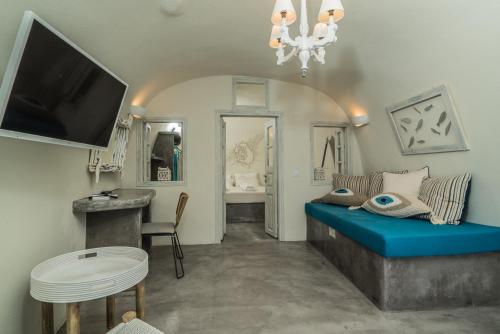 a living room with a blue couch and a tv at Kaleidoscope Cave Houses in Oia