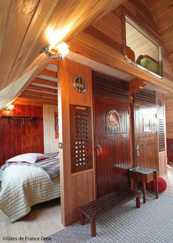 une chambre avec un lit et un miroir au mur dans l'établissement La Cage aux Oiseaux, à La Lande-de-Goult