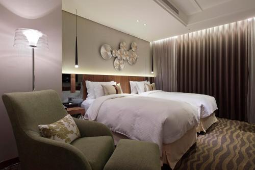 um quarto de hotel com duas camas e uma cadeira em Green World JianPei em Taipei