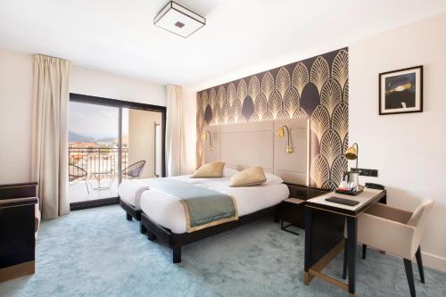 a hotel room with a bed and a desk and a window at Best Western Hôtel Journel Saint-Laurent-du-Var in Saint-Laurent-du-Var