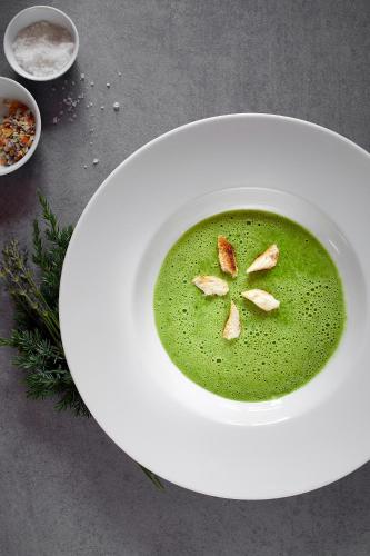 a bowl of green soup on a white plate at Engemann Kurve in Winterberg