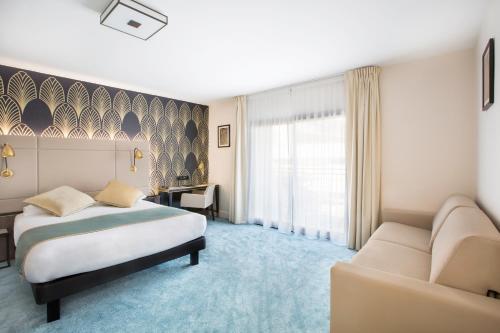 a hotel room with a bed and a couch at Best Western Hôtel Journel Saint-Laurent-du-Var in Saint-Laurent-du-Var