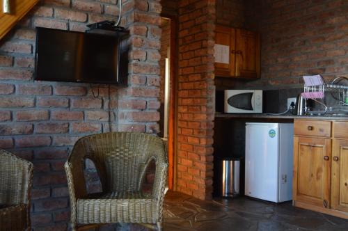 a kitchen with a white refrigerator and a brick wall at Teri-Lemveli Lodge in Beaufort West
