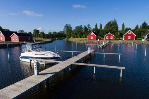 a boat is docked at a dock with red houses at Skandinavisches-Ferienhaus-2-Reihe-zum-Wasser-fuer-6-Personen in Zerpenschleuse