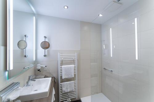 ein weißes Bad mit einem Waschbecken und einer Dusche in der Unterkunft AKZENT Hotel Thiemann in Ganderkesee