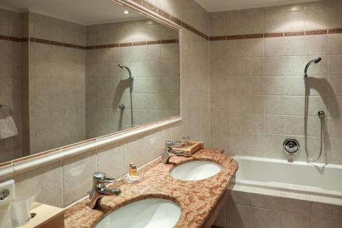 a bathroom with two sinks and a large mirror at Alpenromantik-Hotel Wirlerhof in Galtür