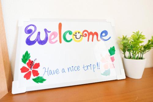 a welcome sign on a table with a plant at Yomitan Ocean View Apartment 403 in Yomitan