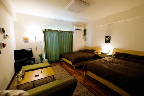 a hotel room with two beds and a television at Yomitan Ocean View Apartment 403 in Yomitan