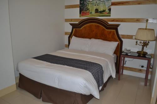 a bedroom with a large bed with a wooden headboard at Metro Vigan Inn in Vigan