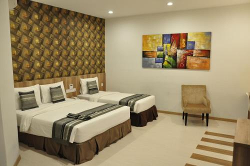 Valya Hotel, Ipoh في ايبوه: غرفة بسريرين ولوحة على الحائط