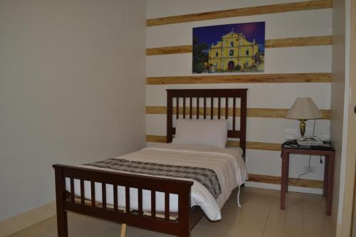 a bedroom with a bed and a table with a lamp at Metro Vigan Inn in Vigan