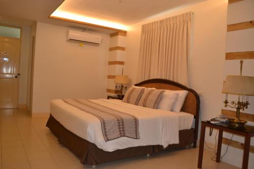 a hotel room with a bed and two tables at Metro Vigan Inn in Vigan