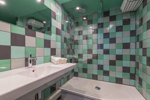 a bathroom with a sink and green and white tiles at Best Western Hôtel Grand Parc Marne La Vallée in Chanteloup-en-Brie