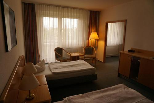 シュテンダールにあるHanse-Hotel Stendalのベッド、テーブル、椅子が備わるホテルルームです。