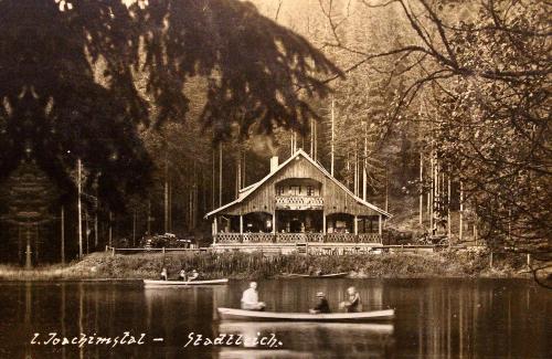 a black and white photo of a house on a lake at Jezírko lesní restaurant & penzion in Jáchymov