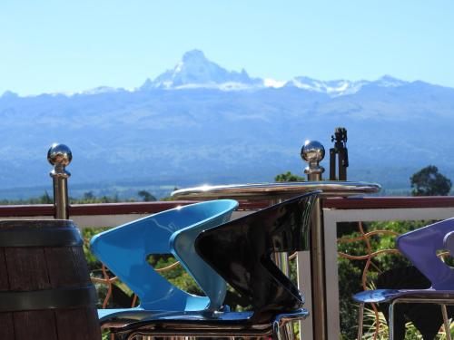 two blue chairs sitting on a balcony with mountains in the background at Misty Mountain Lodge in Naro Moru