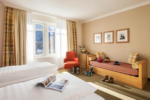 a hotel room with two beds and a chair at Schloss Hotel & Spa Pontresina in Pontresina