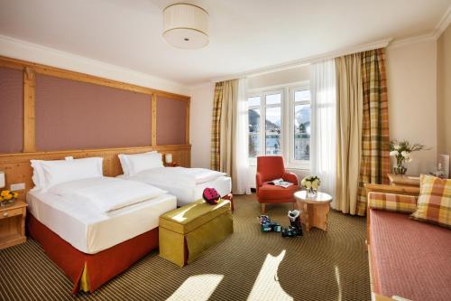 a hotel room with a bed and a couch at Schloss Hotel & Spa Pontresina in Pontresina