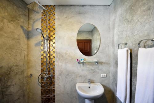 ein Bad mit einem Waschbecken und einem Spiegel in der Unterkunft At Kamala Hotel in Kamala Beach