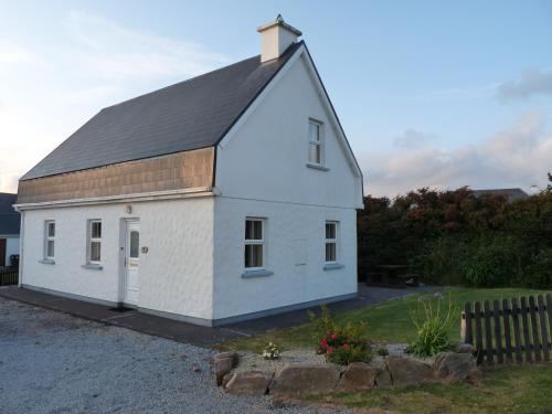 a small white building with a black roof at Skellig Cottages in Ballinskelligs