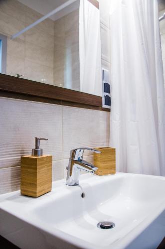 a bathroom sink with a faucet and a mirror at Apartament Centrum Malmeda in Białystok