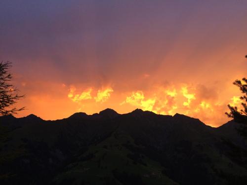 a sunset over a mountain range with the sun setting at Chalet Weidli in Achseten