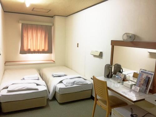 ein Hotelzimmer mit 2 Betten, einem Schreibtisch und einem Schreibtisch in der Unterkunft Hotel Kiyoshi Nagoya No.1 in Nagoya