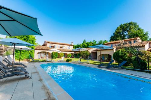 a swimming pool with chairs and umbrellas next to a house at Villa Sévigné in Gréoux-les-Bains