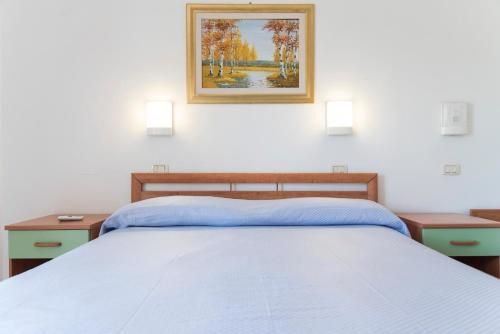 a bedroom with a bed with two night stands and a painting at Hotel Eden in Perdifumo