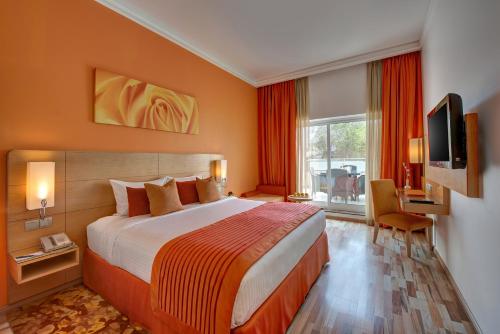 ein Hotelzimmer mit einem großen Bett und einem TV in der Unterkunft Al Khoory Executive Hotel, Al Wasl in Dubai