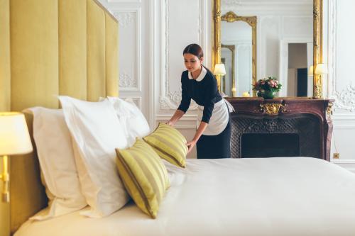 a woman is standing next to a bed at Hôtel Alfred Sommier in Paris