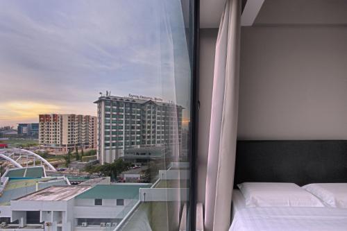 a bedroom with a window with a view of a city at Cozy Living Sky Apartment in Kota Kinabalu
