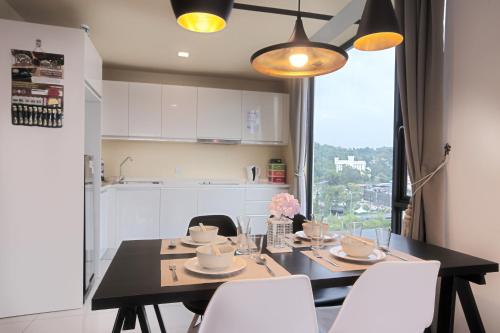a dining room table with white chairs and a kitchen at Cozy Living Sky Apartment in Kota Kinabalu