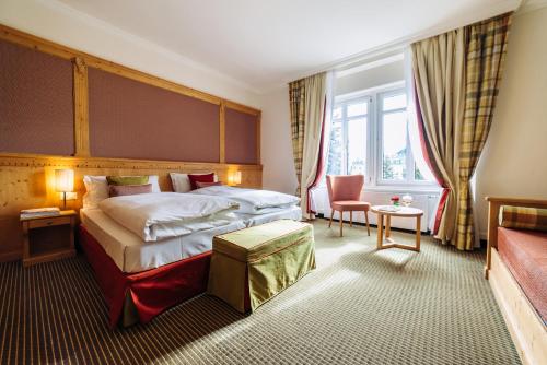 a hotel room with a bed and a chair at Schloss Hotel & Spa Pontresina in Pontresina