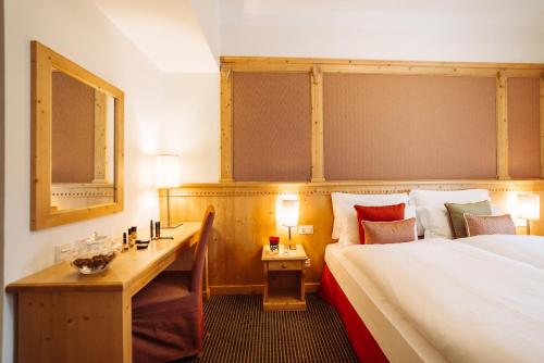 a hotel room with a bed and a desk at Schloss Hotel & Spa Pontresina in Pontresina