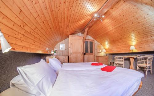 a large bed in a room with a wooden ceiling at Guest House du Grand Paradis - On Piste in Champéry
