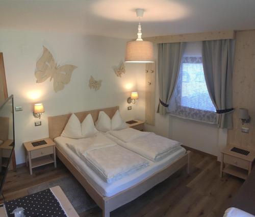 - une chambre avec un lit et un mur aux papillons dans l'établissement Garní Nëidia, à Selva di Val Gardena